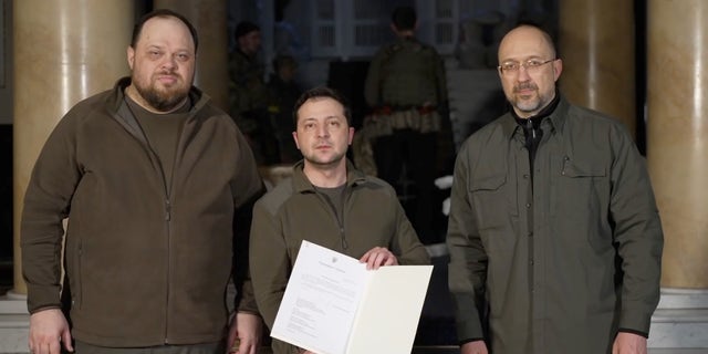 Prime Minister of Ukraine Denys Shmyhal, right, stands with Ruslan Stefanchuk, left, Ukraine President Volodymyr Zelenskyy as he signs an application for the membership of Ukraine in the European Union on Monday Feb 28, 2022.