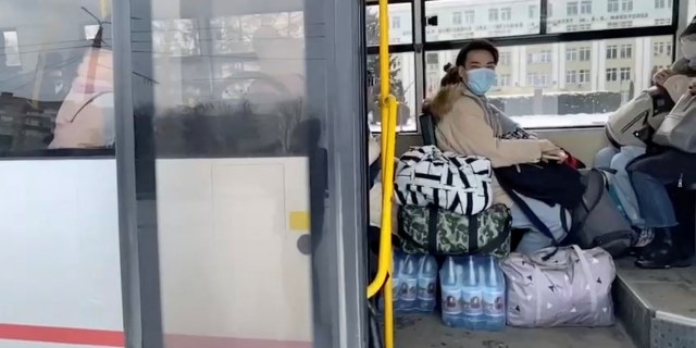 Civilians sit inside a bus with bottled water and belongings during evacuations, amid the Russian invasion of Ukraine, out of Sumy on March 8, 2022.