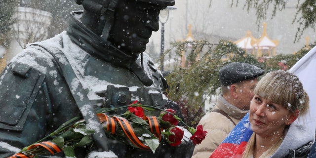 A woman looks at the monument to the so-called "polite people" or the Russian servicemen, who enhanced security during the Crimean referendum to secede from Ukraine and join Russia, during celebrations of the eighth anniversary of Russia's annexation of Crimea in Simferopol, Crimea, March 18, 2022.