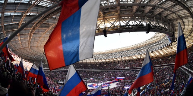People wave Russian flags during a concert marking the eighth anniversary of Russia's annexation of Crimea at Luzhniki Stadium in Moscow March 18, 2022.