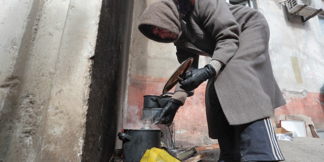 Local resident Antonina, 68, cooks soup in a street during Ukraine-Russia conflict in the besieged southern port city of Mariupol, Ukraine March 20, 2022. (REUTERS/Alexander Ermochenko)