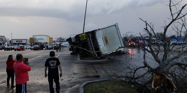 People look at an overturned truck in a parking lot after a tornado in a widespread storm system touched down in Round Rock, Texas, U.S., March 21, 2022.