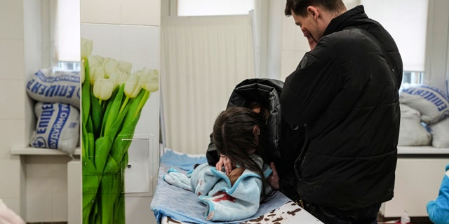 Marina Yatsko, left, and her boyfriend Fedor mourn over her 18 month-old son Kirill's lifeless body, killed in shelling, as he lies on a stretcher in a hospital in Mariupol, Ukraine, Friday, March 4, 2022.