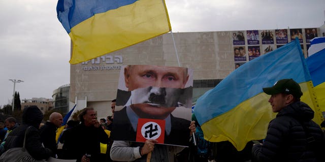 A protester in Habima Square holds a depiction of Russian President Vladimir Putin in Tel Aviv, Israel, as people gather to watch Ukrainian President Volodymyr Zelenskyy in a video address to the Knesset, Israel's parliament.