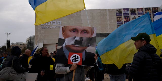 A protester in Habima Square holds a depiction of Russian President Vladimir Putin in Tel Aviv, Israel, as people gather to watch Ukrainian President Volodymyr Zelenskyy in a video address to the Knesset, Israel's parliament.