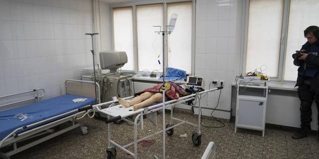 Associated Press photographer Evgeniy Maloletka takes a photo of the lifeless body of a girl, killed from shelling of a residential area, at the city hospital of Mariupol, eastern Ukraine, Feb. 27, 2022. (AP Photo/Mstyslav Chernov)