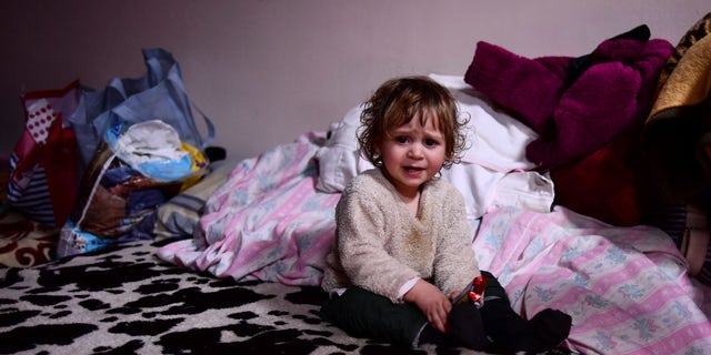 A child sits on a bed in a room hosted by the local Free Christian Church, for those fleeing Ukraine, in the village of Uszka, Hungary, on March 3, 2022. 