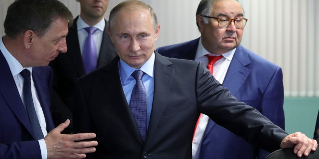 El presidente ruso, Vladimir Putin, en el centro, escucha al director gerente del GOK de Lebedinsky, Oleg Mikhailov, a la izquierda, mientras el empresario y fundador de USM Holdings, Alisher Usmanov, a la derecha, y el ministro de Industria y Comercio, Denis Manturov, se paran detrás de él mientras visitan el JSC del GOK de Lebedinsky, en Gubkin, región de Belgorod, Rusia, viernes 14 de julio de 2017.
