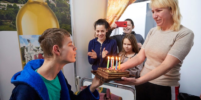 A Ukrainian young man blows the candles on a birthday cake at a facility for refugees in Chisinau, Moldova, Monday, Feb. 28, 2022.