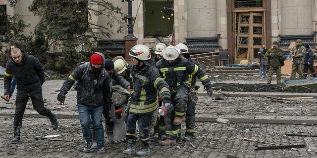Ukrainian emergency service personnel carry a body of a victim out of the damaged City Hall following shelling in Kharkiv, Ukraine, Tuesday, March 1, 2022.