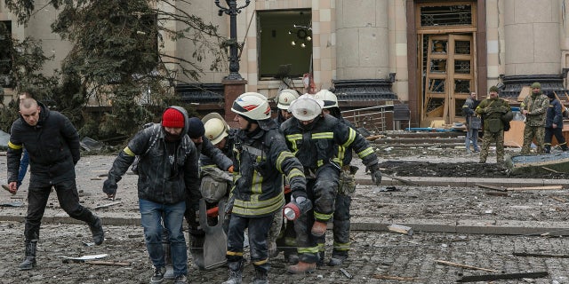 Ukrainian emergency service personnel carry a body of a victim out of the damaged City Hall following shelling in Kharkiv, Ukraine, Tuesday, March 1, 2022.