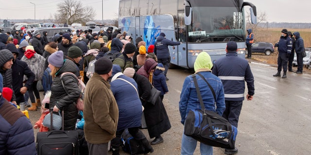 Refugees fleeing war in Ukraine wait to board a bus as they arrive to Palanca, Moldova, Tuesday, March 1, 2022.