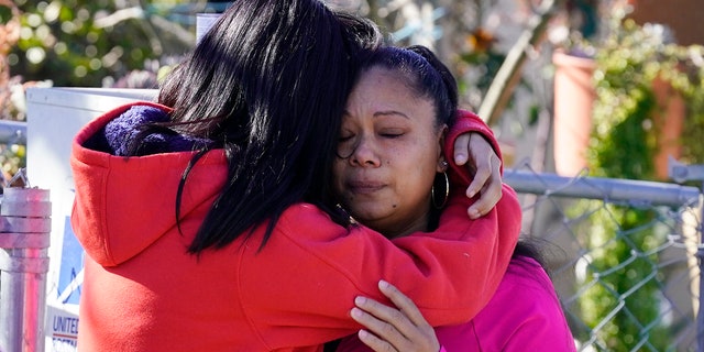 Ana DeJesus, a la derecha, es consolada por su hija, Lizbeth DeJesus, después de colocar un osito de peluche y flores en un monumento en The Church en Sacramento, California, el martes 1 de marzo de 2022.