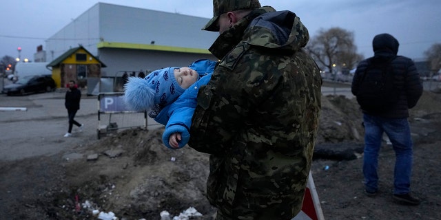A Polish soldier carries a baby of a Ukrainian refugee upon their arrival at the border crossing in Medyka, southeastern Poland, Wednesday, March 2, 2022.