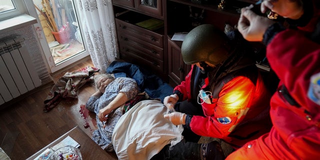Ambulance paramedics treat an elderly woman wounded by shelling before transferring her to a maternity hospital converted into a medical ward in Mariupol, Ukraine, on Wednesday, March 2, 2022. 