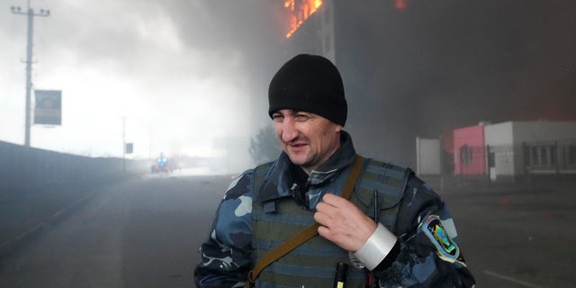 A Ukrainian serviceman walks as fire and smoke rise over a building following shelling in Kyiv, Oekraïne, Donderdag, Maart 3, 2022. Russia has launched a wide-ranging attack on Ukraine, hitting cities and bases with airstrikes or shelling.