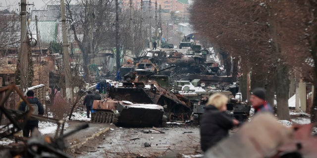People look at the gutted remains of Russian military vehicles on a road in the town of Bucha, close to the capital Kyiv, Ukraine on March 1. Russian forces have struggled to make progress in Ukraine amid heavy fighting and fierce resistance.