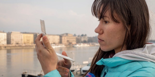 Olena, a Russian citizen fleeing from Kyiv, Ukraine (no family name given for safety reason) looks at herself in a mirror after arriving in Budapest, Hungary on Friday, March. 4, 2022.
