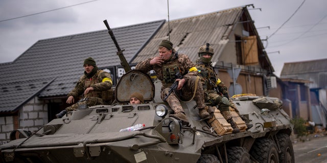 Ukrainian soldiers drive on an armored military vehicle in the outskirts of Kyiv, Ukraine, Saturday, March 5, 2022. (AP Photo/Emilio Morenatti)