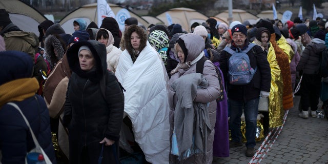 Refugees wait for transportation after fleeing from Ukraine and arriving at the border crossing in Medyka, Poland, Monday, March 7, 2022.