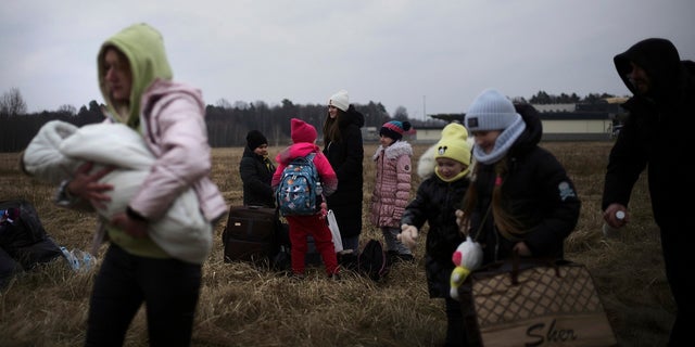 A woman holds a baby as she walks with other who have fled Ukraine, at the border crossing in Budomierz, Poland, Monday, March 7, 2022. 