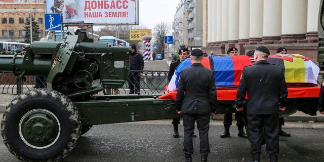 Servicemen stand next to the coffin with the body of Col. Vladimir Zhoga, commander of a reconnaissance battalion of the self-proclaimed Donetsk People Republic, during a farewell ceremony in Donetsk, eastern Ukraine, Monday, March 7, 2022.