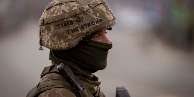 A Ukrainian soldier stands guard at a checkpoint on the outskirts of Kyiv, Ukraine.