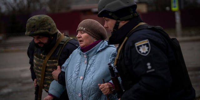 Ukrainische Polizisten helfen einer Frau bei der Flucht, als Artillerie in der Nähe von Irpin am Stadtrand von Kiew, Ukraine, ertönt, Montag, 7. März 2022.