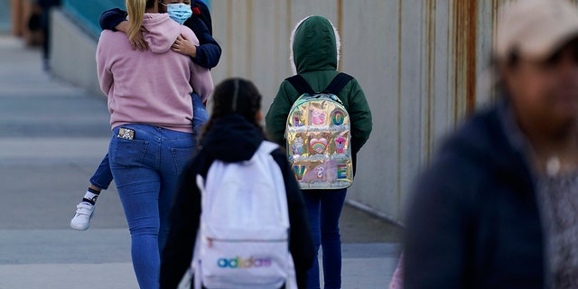 Children and their caregivers arrive for school in New York, Monday, March 7, 2022. New York City passed a COVID-19 milestone on Monday as masks became optional in city schools and restaurants and other businesses could stop asking patrons for proof of vaccination. (AP Photo/Seth Wenig)