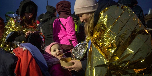 A woman feeds her daughter after fleeing Ukraine and arriving at the border crossing in Medyka, Poland, Monday, March 7, 2022. (AP Photo/Visar Kryeziu)