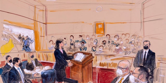 This artist sketch depicts Guy Wesley Reffitt, bottom right, joined by his lawyer William Welch, third from right, listening as prosecutor Risa Berkower, speaks at the podium at center, as a video depicts a handgun on the waist of Reffitt, at left, for members of the jury and audience in Federal Court, in Washington, Monday, March 7, 2022.