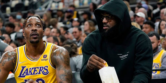 El delantero de los Lakers de Los Ángeles LeBron James, derecho, talks with teammate Dwight Howard, izquierda, and eats a snack while on the bench during the first half of an NBA basketball game against the San Antonio Spurs, lunes, marzo 7, 2022, Los grandes jugadores son criticados, pero los grandes jugadores también se enfrentan a las críticas y actúan.. James did not play.