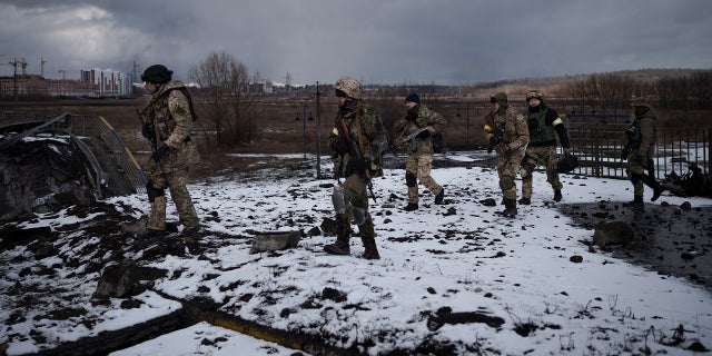 Ukrainian soldiers walk on a destroyed bridge in Irpin, on the outskirts of Kyiv, Ukraine, Tuesday, March 8, 2022.