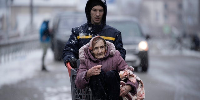 An elderly lady is carried in a shopping cart after being evacuated from Irpin, on the outskirts of Kyiv, Ukraine, Tuesday, March 8, 2022. 