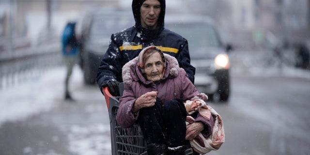An elderly lady is carried in a shopping cart after being evacuated from Irpin, on the outskirts of Kyiv, Ucraina, martedì, marzo 8, 2022.