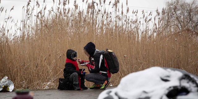 Tatiana Kostyuk, 38, from Zaporozhye, gives food to a child after fleeing Ukraine, at the border crossing in Medyka, Poland, Wednesday, March 9, 2022.