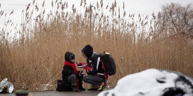 Tatiana Kostyuk, 38, from Zaporozhye, gives food to a child after fleeing Ukraine, at the border crossing in Medyka, Poland, Wednesday, March 9, 2022.