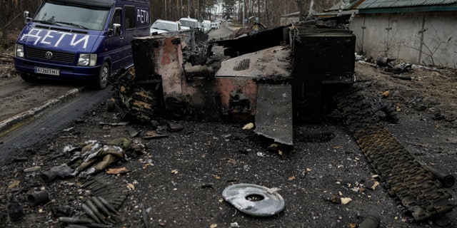 A van with the word "Children" written on it drives past a destroyed Russian tank as a convoy of vehicles evacuating civilians, leaves Irpin, on the outskirts of Kyiv, Ukraine, Wednesday, March 9, 2022. A Russian airstrike devastated a maternity hospital Wednesday in the besieged port city of Mariupol amid growing warnings from the West that Moscow's invasion is about to take a more brutal and indiscriminate turn.