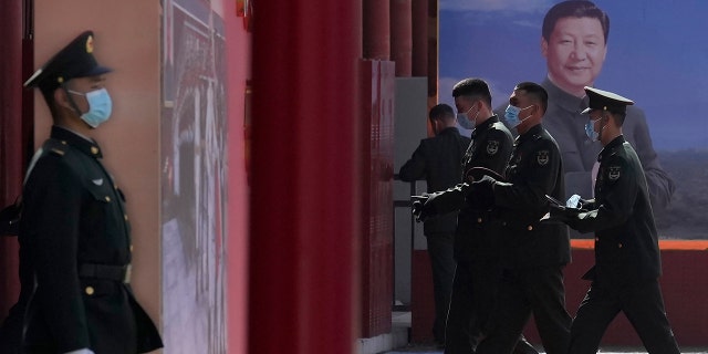 Chinese military personnel pass by a board displaying a photo of Chinese President Xi Jinping on March 4, 2022, in Beijing.
