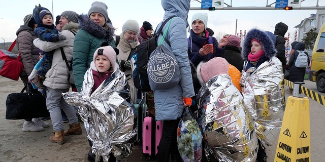 Refugees stand in a group after fleeing war from neighboring Ukraine at the border crossing in Palanca, Moldova, Thursday, March 10, 2022.