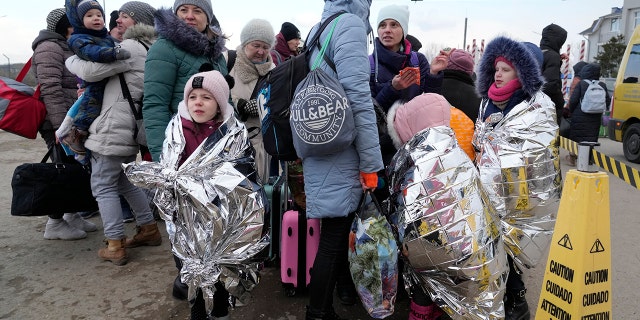 Refugees stand in a group after fleeing war from neighboring Ukraine at the border crossing in Palanca, Moldova, Thursday, March 10, 2022.