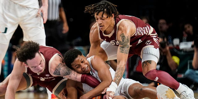 Miami's Charlie Moore, center, Boston College's Jaeden Zackery, left, and Makai Ashton-Langford, right, battle for the ball in the first half of an NCAA college basketball game during quarterfinals of the Atlantic Coast Conference tournament, Thursday, March 10, 2022, in New York.