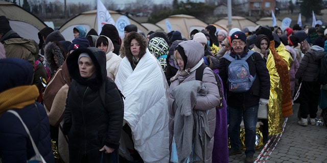 Refugees wait in a crowd to be transported after fleeing Ukraine and arriving at the border crossing in Medyka, Poland, Monday, March 7, 2022. (AP Photo/Markus Schreiber, File)