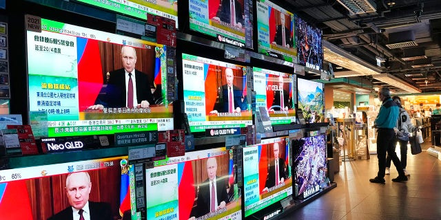 People in Hong Kong stand by TV screens broadcasting the news that Russian troops have launched an attack on Ukraine, Feb. 24, 2022.