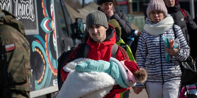 A man holds a baby after fleeing from Ukraine at the border crossing in Medyka, southeastern Poland, on Friday, March 11, 2022. Thousands of people have been killed and more than 2.3 million have fled the country since Russian troops crossed into Ukraine on Feb . 24.