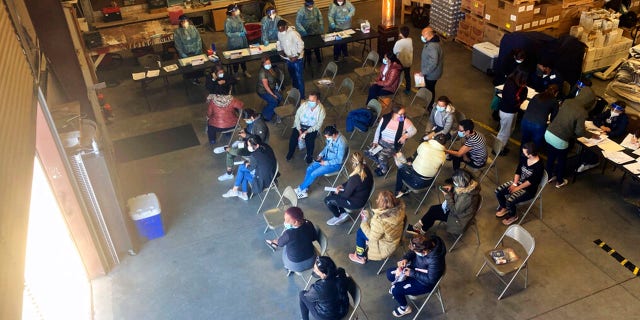 Migrants released by the Border Patrol with notices to appear in court in Somerton, Ariz., wait for COVID-19 testing at a Regional Center for Border Health warehouse before being taken by charter bus to the Phoenix Sky Harbor International Airport Feb 5, 2022.