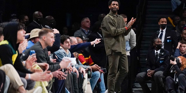 Brooklyn Nets' Kyrie Irving watches the game from his seats during the second half of the NBA basketball game between the Brooklyn Nets and the New York Knicks at the Barclays Center, 星期日, Mar. 13, 2022, 在纽约. The Nets defeated the Knicks 110-107.