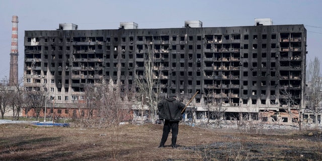 A man looks at a burned apartment building that was damaged by shelling in Mariupol, Ukraine, Sunday, March 13, 2022. 