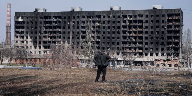 A man looks at a burned apartment building that was damaged by shelling in Mariupol, Ukraine, Sunday, March 13, 2022.