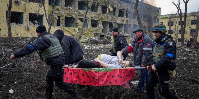 Ukrainian emergency employees and volunteers carry an injured pregnant woman from a maternity hospital damaged by shelling in Mariupol, Ukraine, Wednesday, March 9, 2022. The baby was born dead. Half an hour later, the mother died too. (AP Photo/Evgeniy Maloletka)